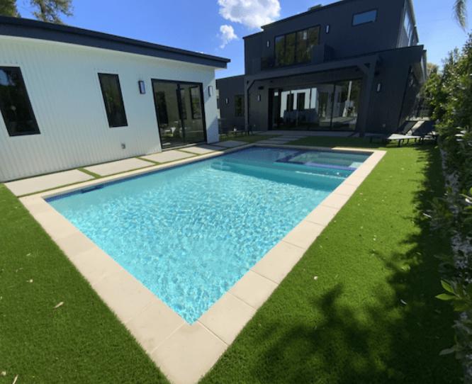 A private rectangular pool with a built-in spa, surrounded by lush greenery and stone flooring in Pasadena.