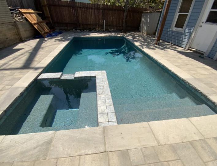 A modern backyard pool renovation featuring a sleek design and integrated spa.