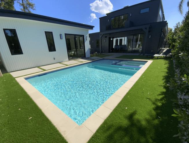 A remodeled pool with modern blue tilework, an upgraded spa, and elegant landscaping.