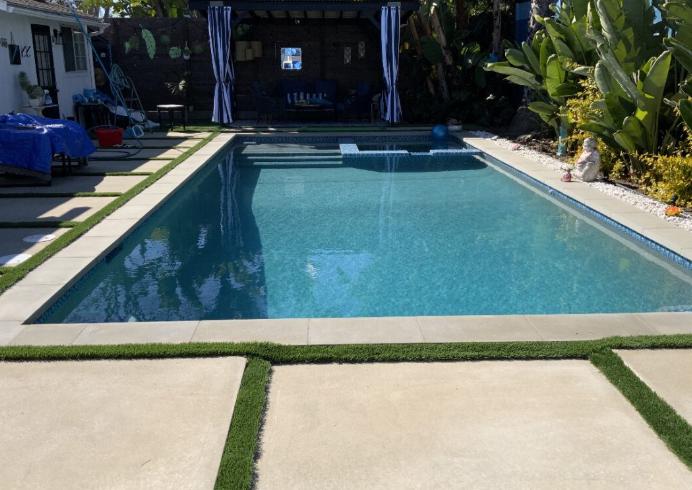 A beautifully renovated pool with elegant landscaping and custom features.